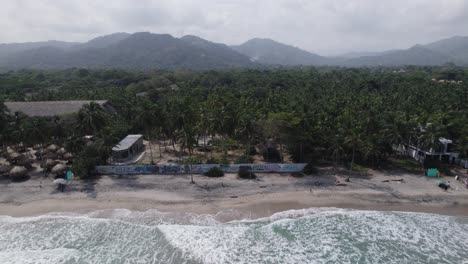 Vista-Lateral-Del-Carro-Aéreo-De-La-Playa-De-Arena-Con-Un-Exuberante-Paisaje-Tropical-De-Palomino