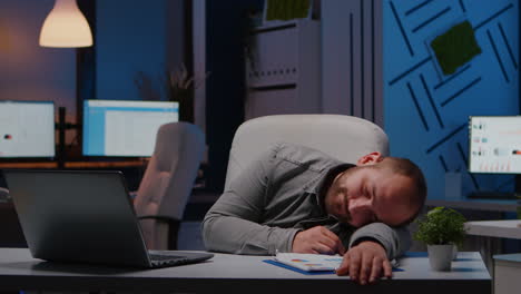 exhausted overworked businessman sleeping on desk table in startup business office