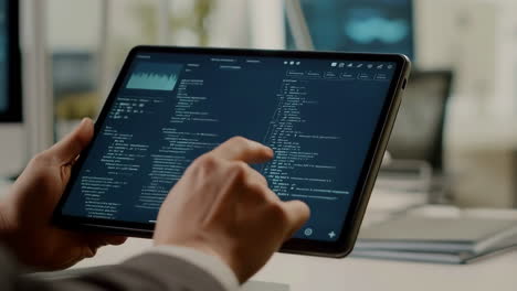 close-up of hands interacting with a tablet displaying code and data