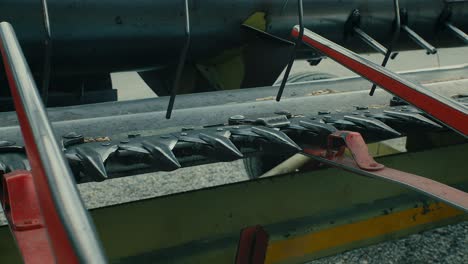 red farm machinery at work, close angle of cutting apparatus, daytime