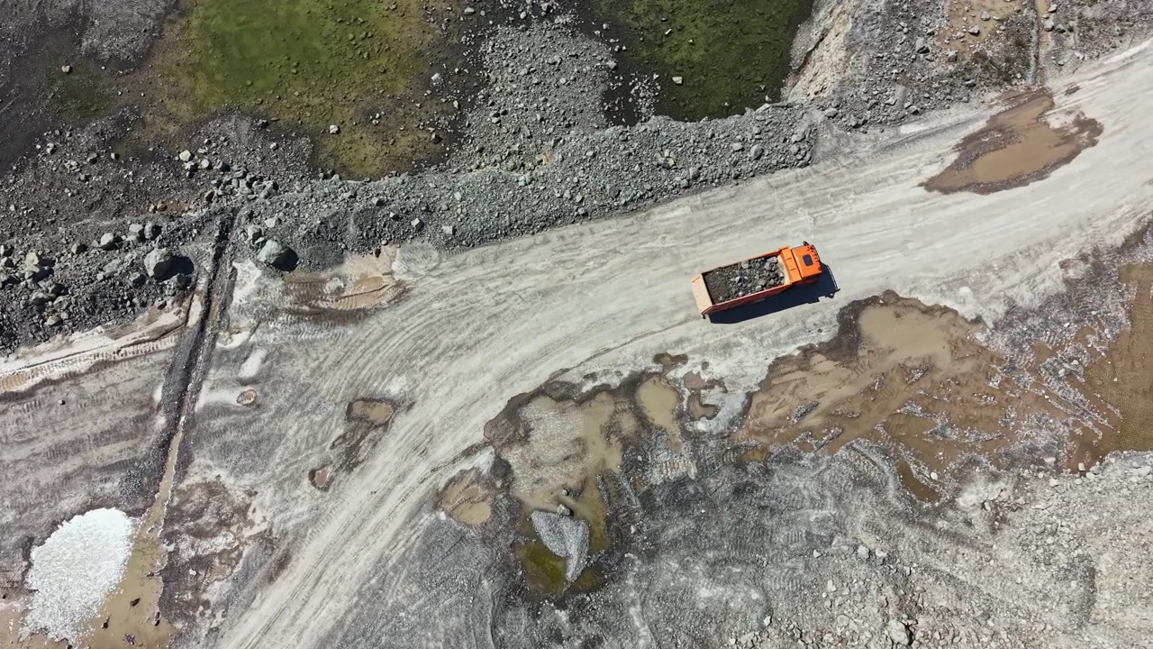 Granite quarry near a construction site with a truck transporting materials on a gravel road under clear sky