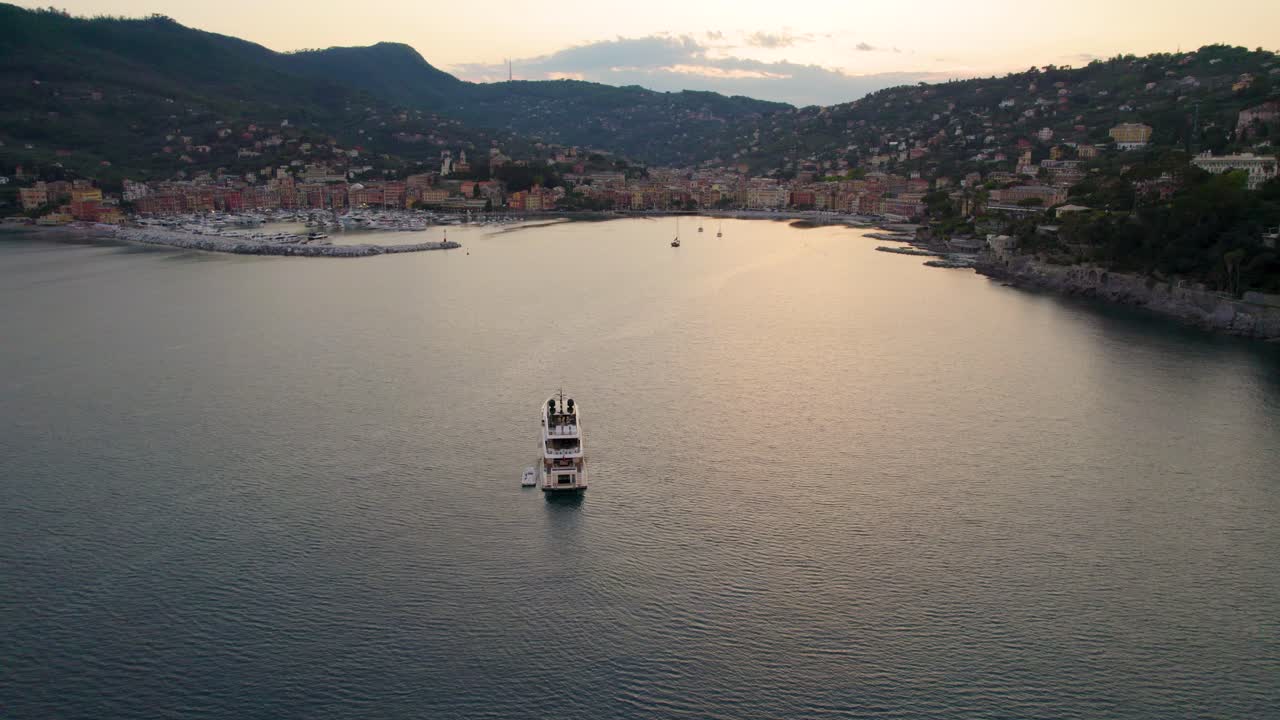 Yacht che naviga appena fuori dal porto di una località turistica, Liguria.