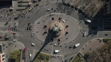 Top-down-static-shot-of-vehicles-passing-around-Columbus-Monument.-Statue-on-tall-column-in-centre-of-oval-roundabout.-Barcelona,-Spain