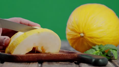 herb men cut a melon into pieces on a wooden cutting board.