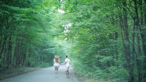 forest road landscape with couple. pretty young couple in love having fun on the forest road