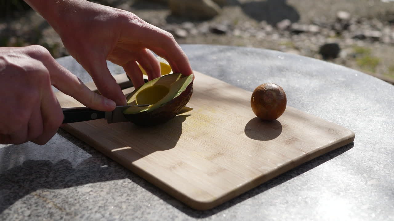 cortar un aguacate con un cuchillo en una tabla de cortar para una comida vegana saludable
