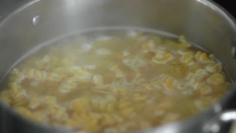 pasta in boiling water inside a silver pot as steam rises