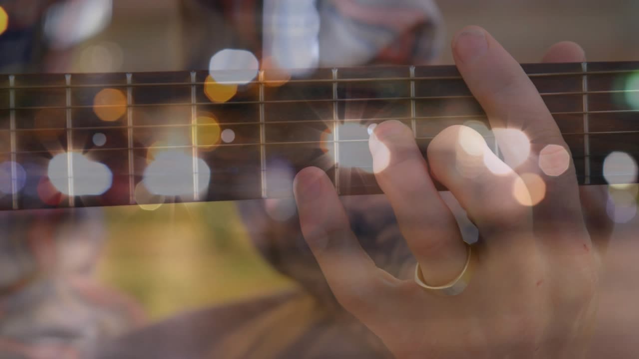 Musician left hand pressing strings, initiating chord shift during music tutorial with bokeh lights