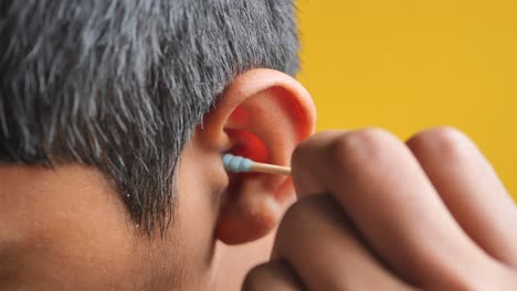 boy cleaning his ear with a cotton swab