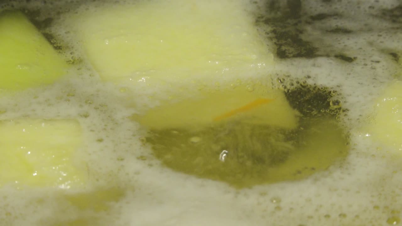 Chunks of potatoes and vegetables boiling in a pot of water, forming the base for a hearty homemade soup or stew