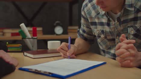 mano masculina de primer plano firmando un contrato de bienes raíces y estrechando la mano con el corredor