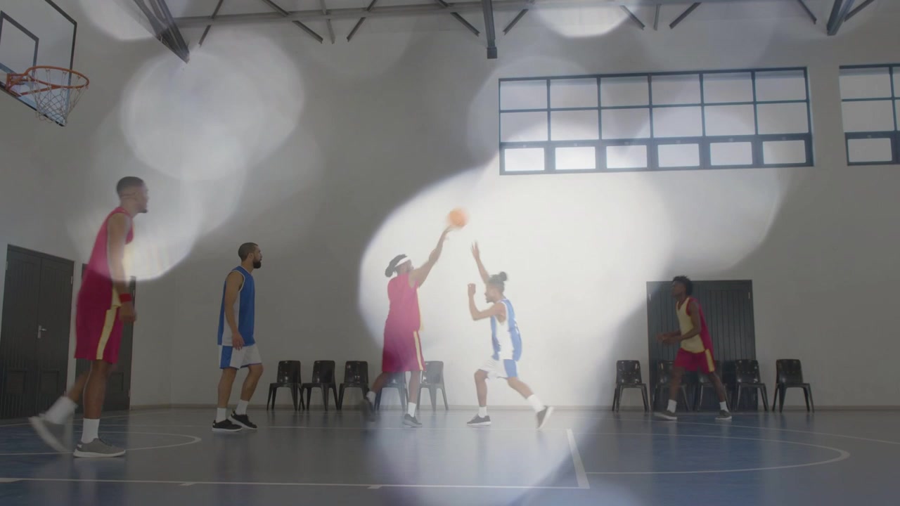 Squadra di basket maschile dopo che il giocatore in blu ha palleggiato, il giocatore in rosso tira per segnare, con effetto bokeh che sfuma