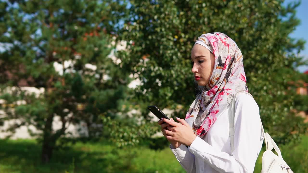 Young Woman with Hijab Using Smartphone Outdoors