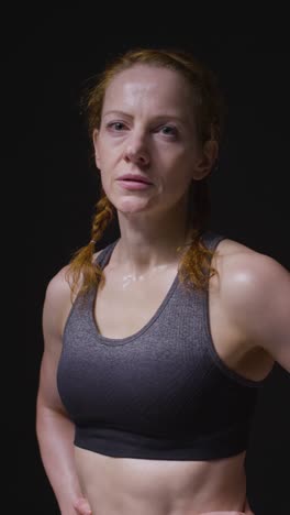 vertical video studio portrait of mature woman wearing gym fitness clothing sweating recovering after exercise