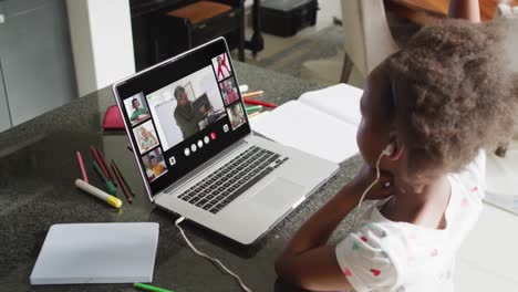 chica afroamericana usando una computadora portátil para una llamada de video, con un maestro masculino y una clase en la pantalla