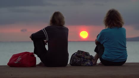 two women watch sunset at ala moana beach park in honolulu hawaii