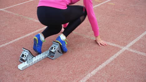 Female-athlete-taking-starting-position-on-running-track-4k