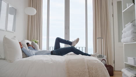 happy man jumping on bed in hotel room resting after successful travel journey smiling enjoying independent lifestyle freedom