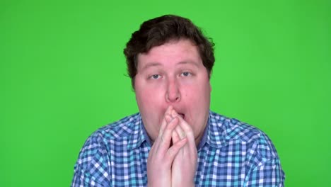 close up shot of a sick man in plaid shirt caughing and sneezing. background is green screen.