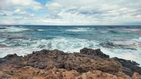 Amplia-Vista-Del-Mar-Mediterráneo-Desde-Chipre,-Mostrando-Olas-Rompiendo-Contra-La-Costa-Rocosa-Bajo-Un-Cielo-Parcialmente-Nublado