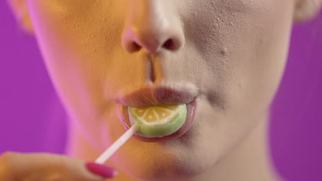 mujer lamendo helado con seducción, boca en primer plano en fondo púrpura