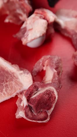 raw pork and bones on a red cutting board