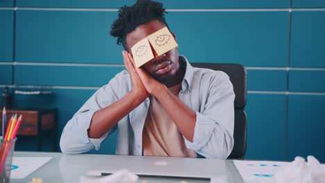 young african american man office worker sleeps sits at desk in office