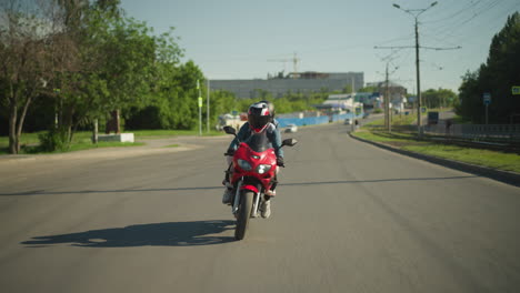 two sisters on a red power bike navigate along an urban road, with a blurred view of people walking along the path and cars approaching from behind