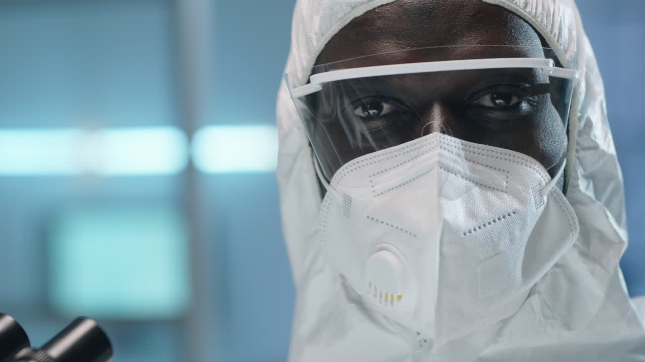 портрет черного лабораторного ученого в защитном костюме и маске