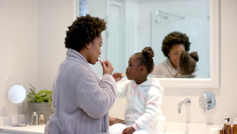 joven madre afroamericana se cepilla los dientes con su hija afroamericana en casa