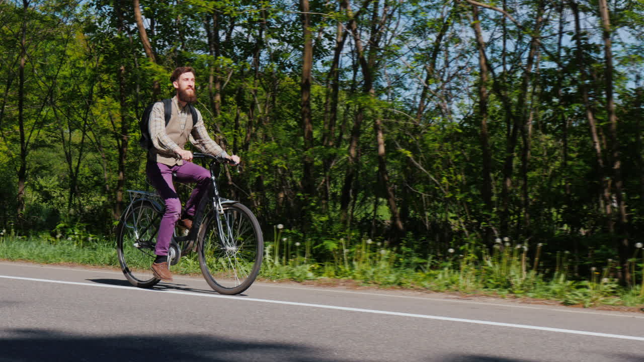 턱수염을 기른 매력적인 남자가 자전거 도로를 따라 자전거를 탄다