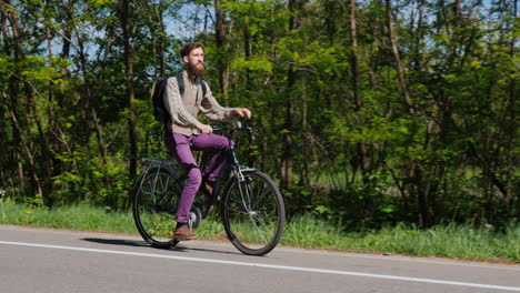 an attractive man with a beard rides a bike along a bicycle path