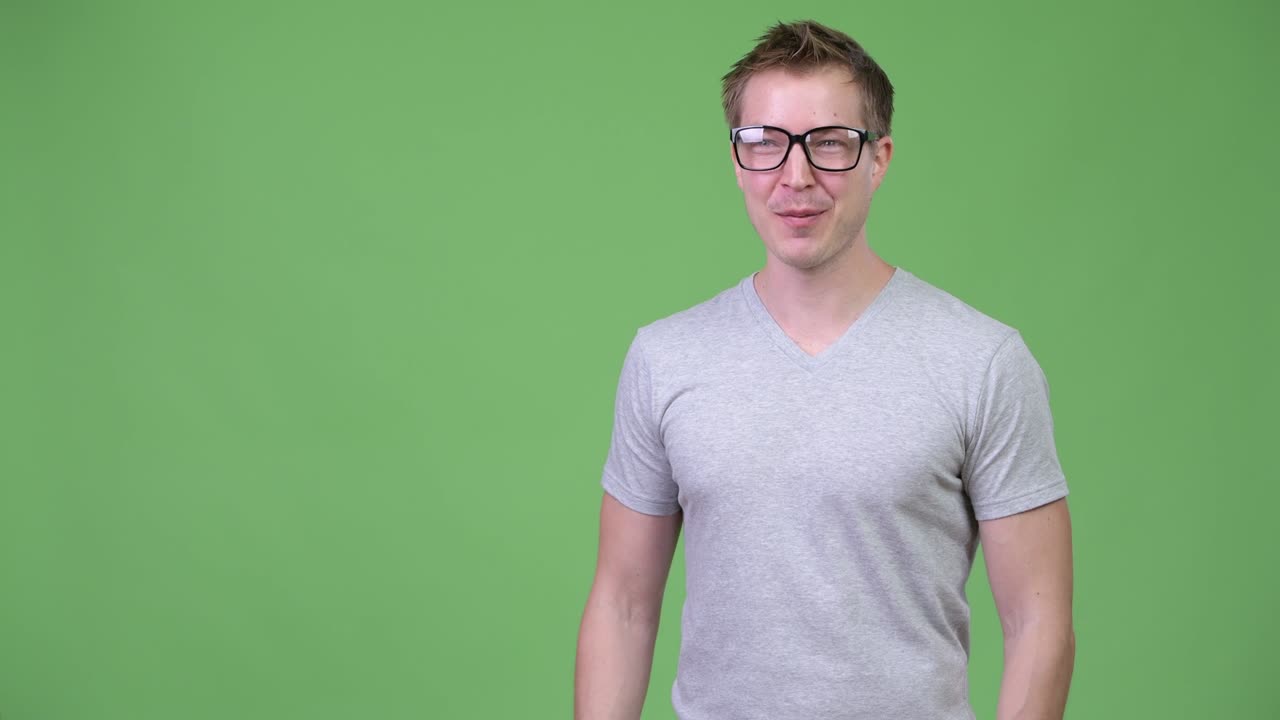 Young handsome nerd man talking against green background