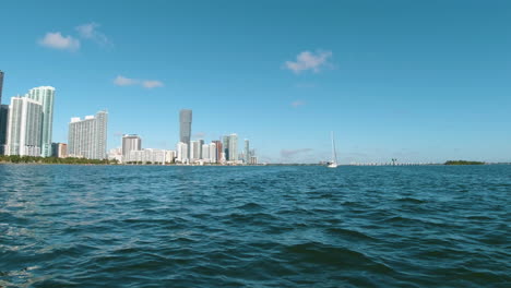 the city of miami from the view of a small watercraft with a sailboat nearby