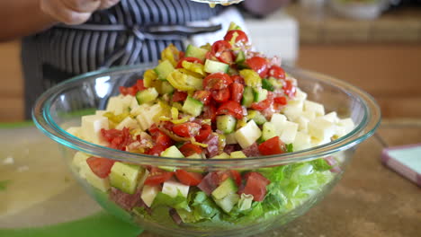 dumping the wet ingredients: pickled pepper, sauerkraut, olive oil, vinegar, tomatoes to the chopped salad - antipasto salad series