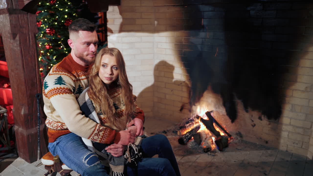Beautiful couple in love near fireplace. Loving man and woman inside hugging in cold evening.
