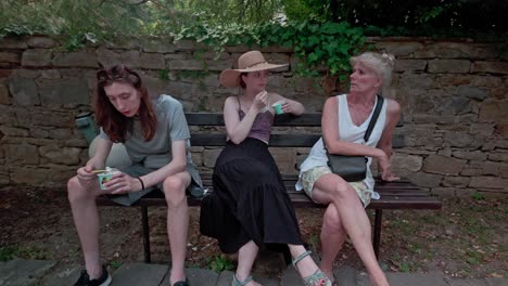 young sweethearts enjoy ice cream talk with mother on park bench