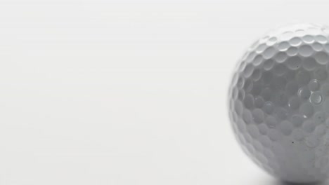 close up of golf ball on white background, copy space, slow motion