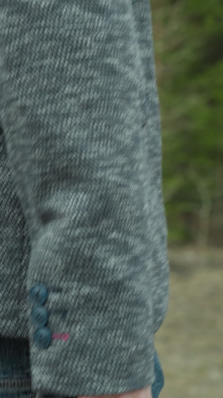 회색 재과 파란 청바지를 입은 남자가 숲길을 고 있는 모습