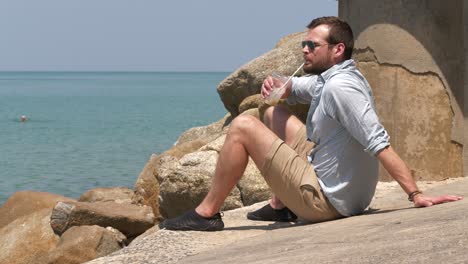 man sips drinks and relaxes contemplating sea