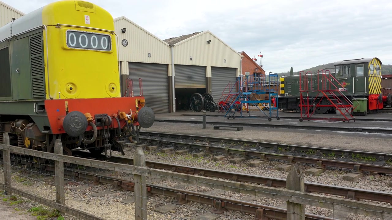 Un'inquadratura statica di classici treni diesel britannici parcheggiati fuori dai capannoni di manutenzione in una stazione ferroviaria storica. Adatto per la storia dei trasporti e documentari industriali