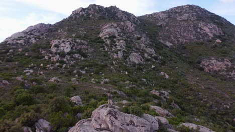 Hiker-standing-on-a-rock-and-enjoying-the-view-over-a-beautiful-rocky-landscape-in-Sardinia