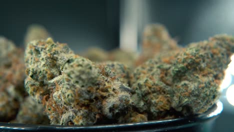 una toma hiper macro soñadora y constante de una planta de cannabis, cepas híbridas de naranja, sativa, flor de marihuana, en un soporte giratorio, cámara lenta, video 4k, iluminación de estudio