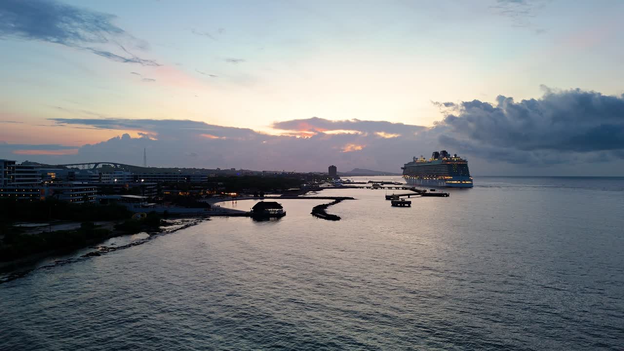 el dron se levanta de la playa mientras un gran crucero atracado en el puerto se enciende a la hora azul en el caribe.