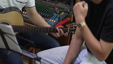 musician strumming acoustic guitar, focus on fretboard