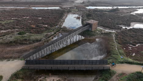 Paisaje-Aéreo-De-Puentes-De-Madera-Estartit-En-Costa-Brava,-Ciclista-Pasando