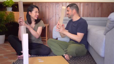 Multiracial-couple-assembling-table-on-rug-in-house