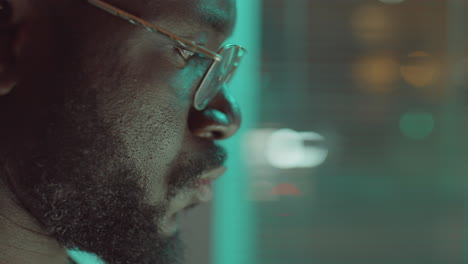 african american man in glasses using laptop during night