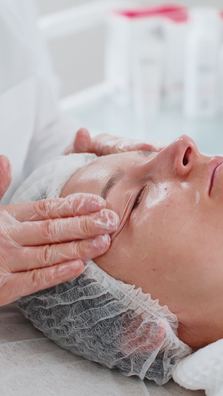 cosmetólogo aplicando crema hidratante especial exfoliando la cara de una bonita mujer caucásica niña