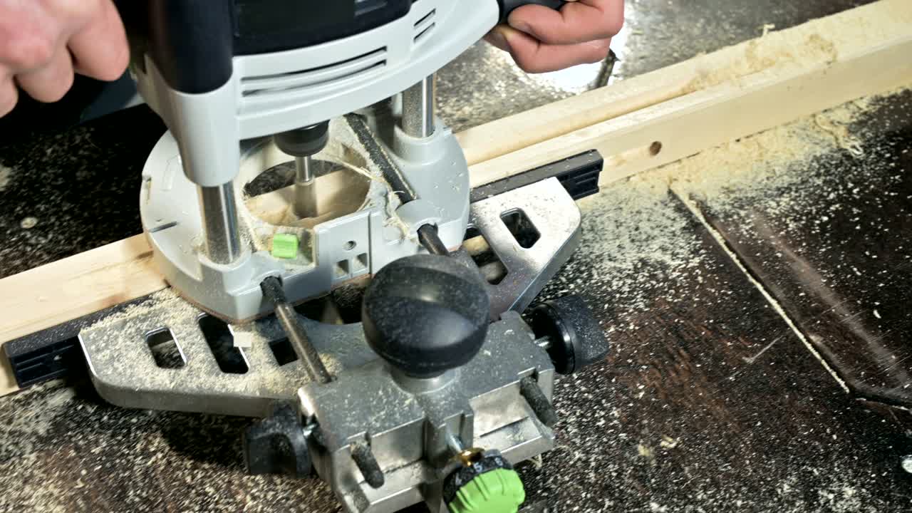 primer plano de la mano de un carpintero trabajando con un cortador eléctrico manual en un taller casero.